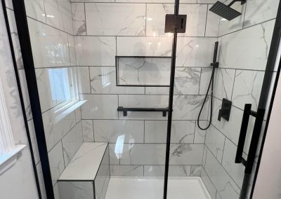 Luxury modern bathroom remodel featuring black matte fixtures, marble tile shower, and custom bench in CT